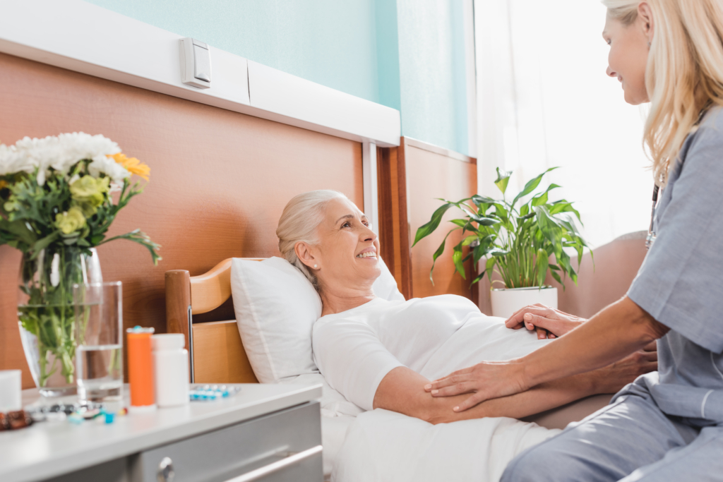 Caregiver adjusting bedding for a bedridden loved one, ensuring comfort and cleanliness in a home care environment.